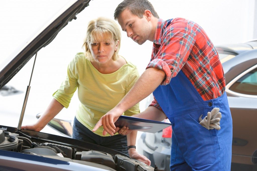 Auto mechanic and car owner looking at the engine