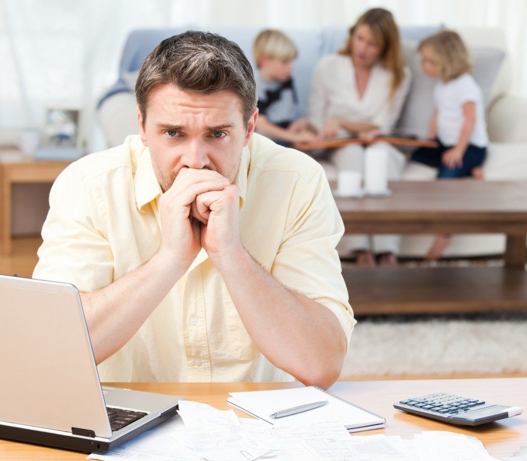 Man worried about bills with family in the background