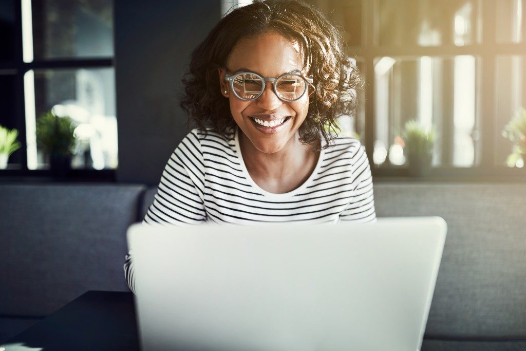 woman smiling while doing her work on a laptop