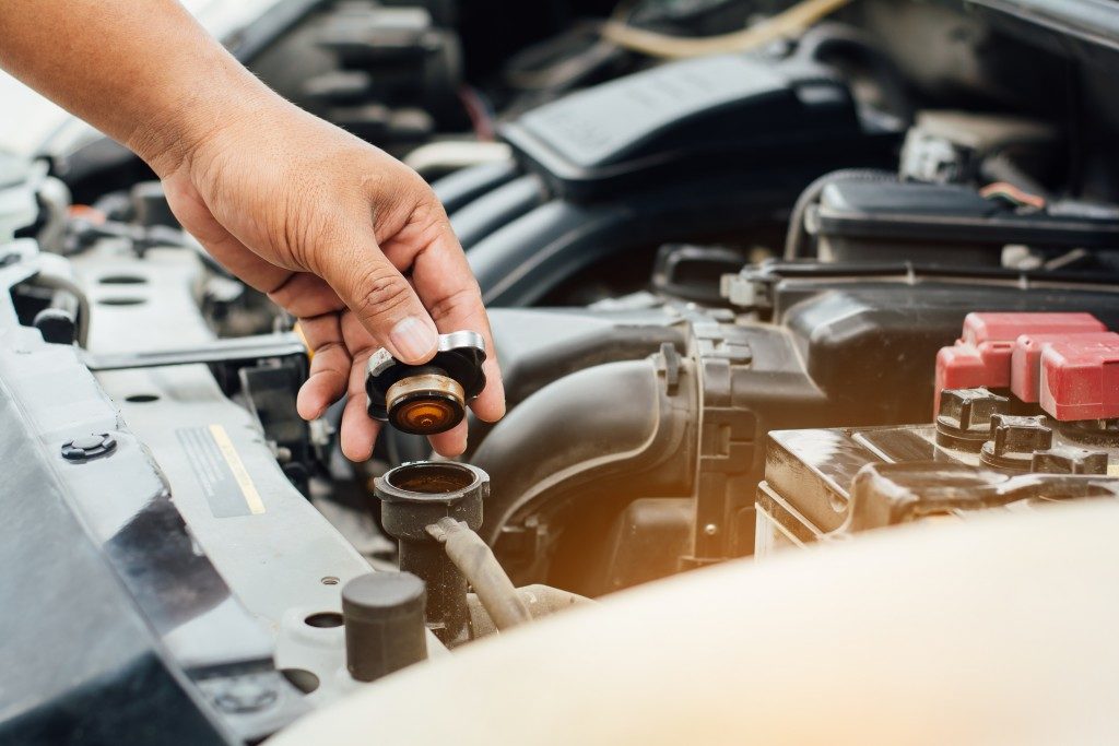 hand of a person closing the container at the car's engine after changing the transmission fluid 