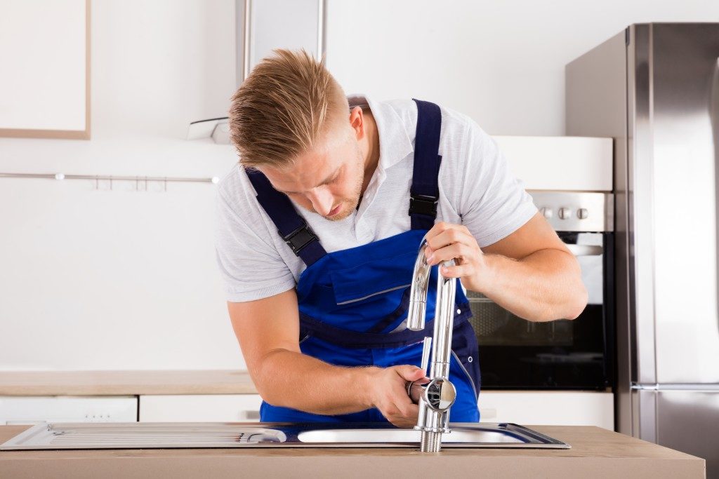 Man installing new sink faucet in the kitchen