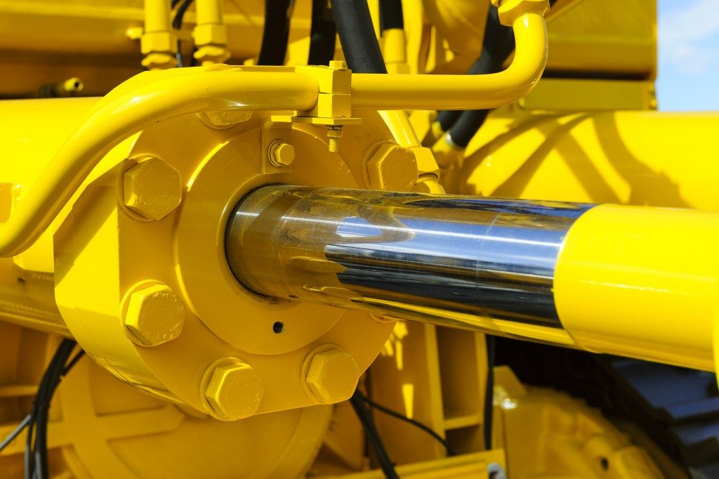 Hydraulic piston system for bulldozers, tractors, excavators, chrome plated cylinder shaft of yellow machine, construction heavy industry detail, selective focus