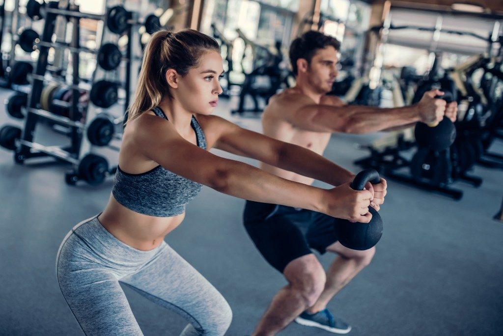 Man and woman lifting weights at the gym