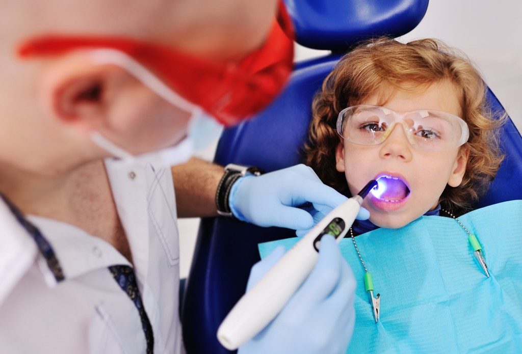 Little boy having his teeth checked by the dentist