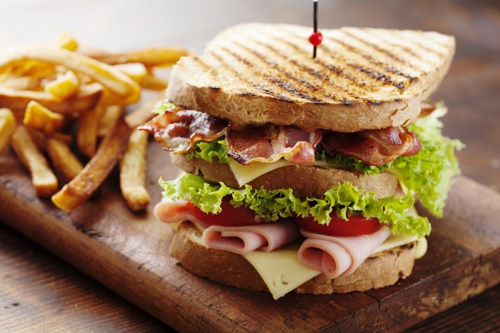 Club sandwich with fries served on wood