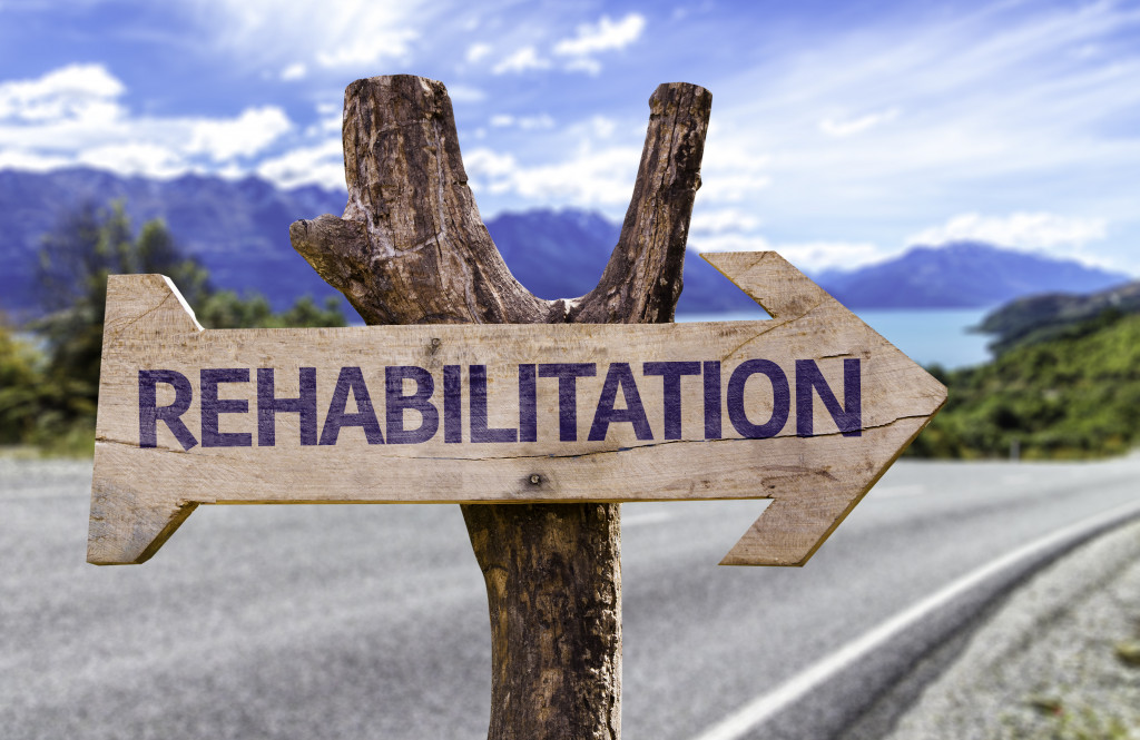 road sign nailed to a tree stump with the word rehabilitation pointing with an arrow