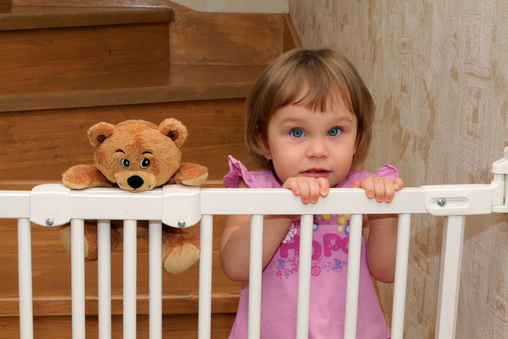 little girl and teddy bear by the gate