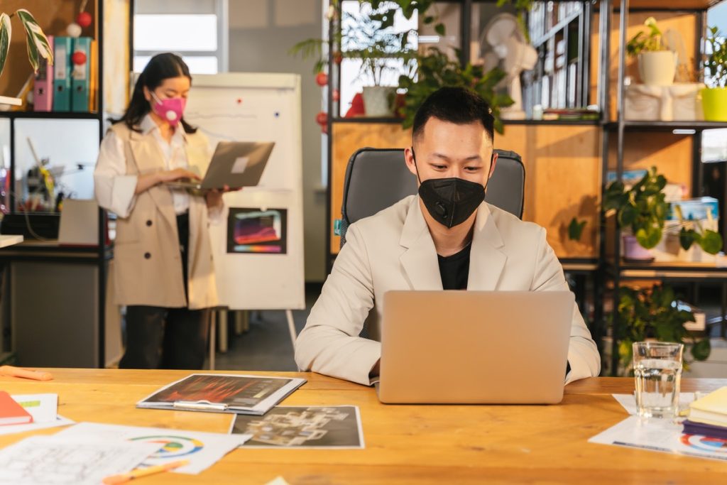 employees working on their laptop while wearing masks