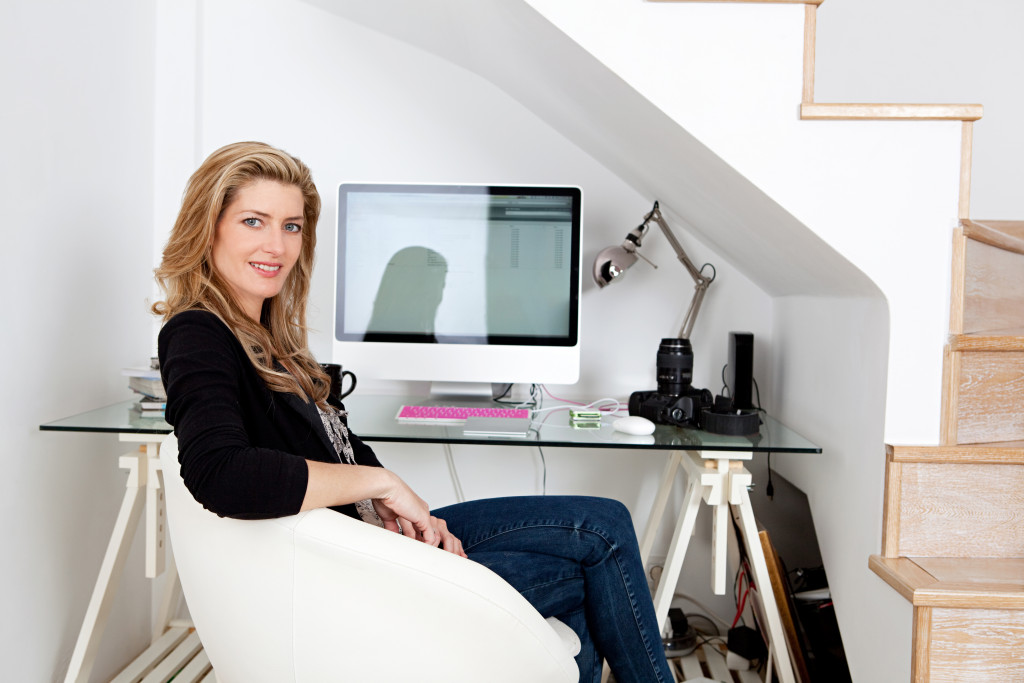 Young professional photographer working from home and sitting at her desk at home, with her camera equipment