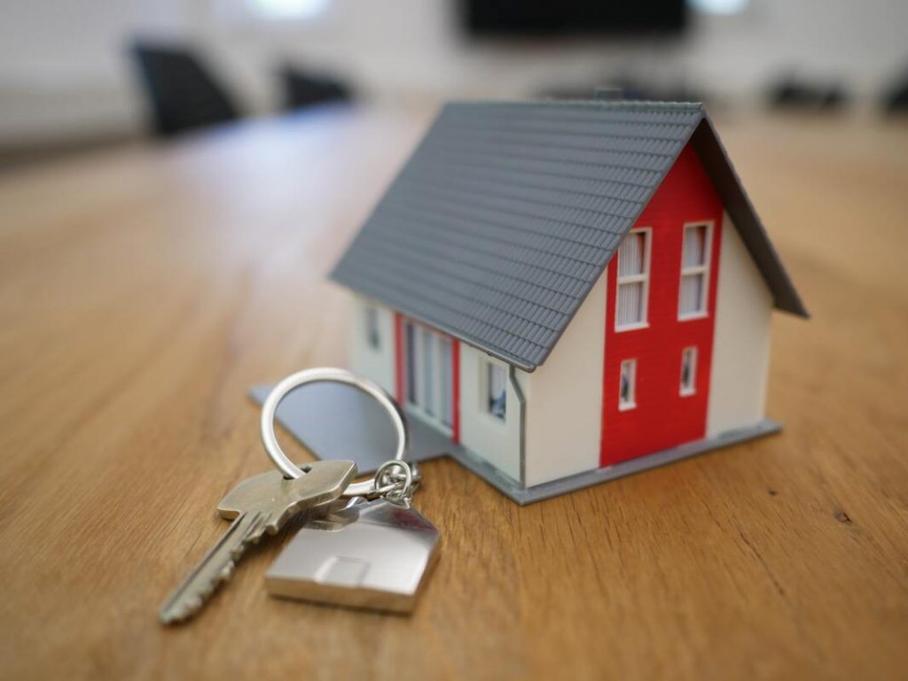 miniature house with a key besite it conceptualizing real estate