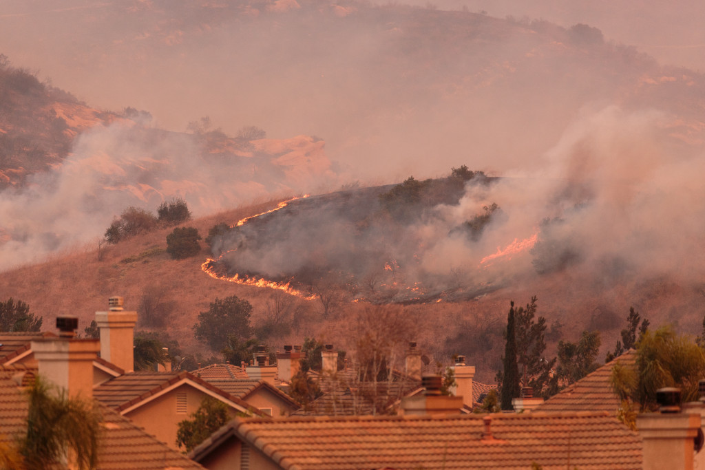 A wildfire on a hill near a residential area