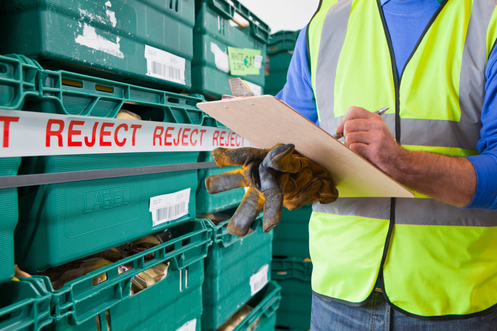 A worker checking containers with rejected produce in a food processing facility