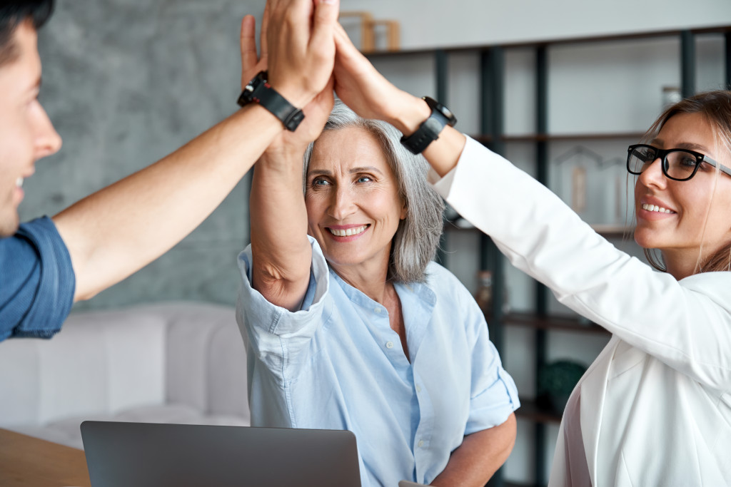 an elderly female boss high fiving with younger employees