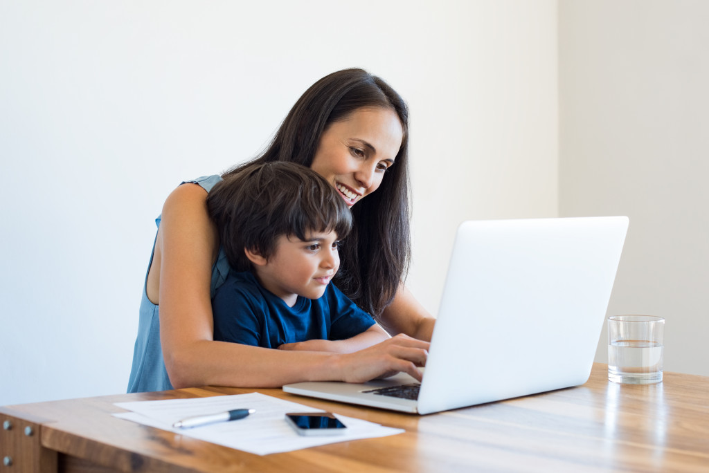 a mother using a laptop with child on her lap