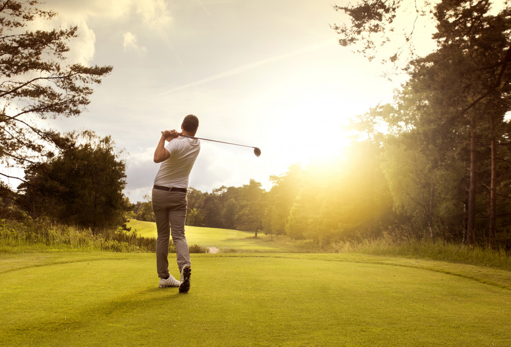 a man hitting a golf ball with the sunf
