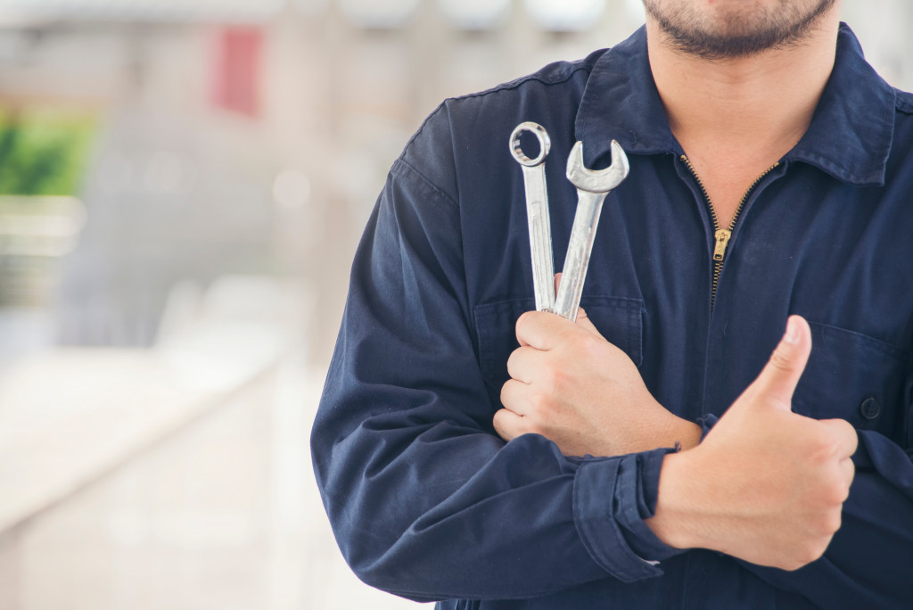 a repairman holding wrench and tool in his hand with thumbs up on the other