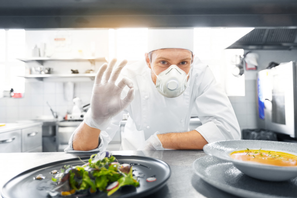 A restaurant chef wearing a face mask to protect food preparation in the restaurant kitchen