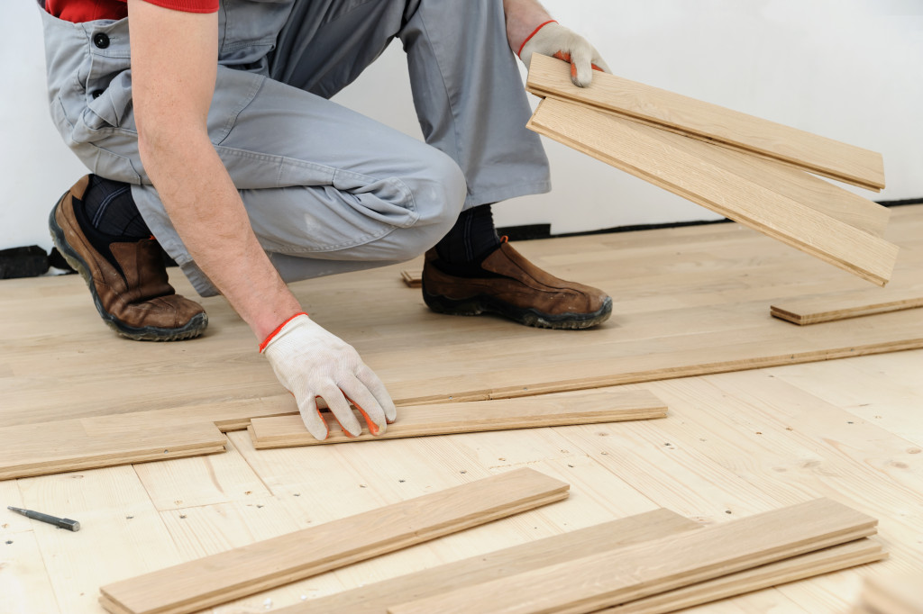 man measuring wooden planks for hardwood flooring