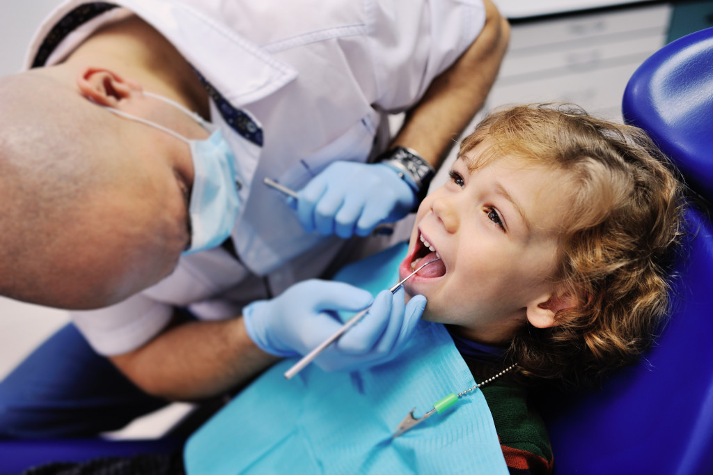 dentist inspecting little boy's teeth in dental clinic