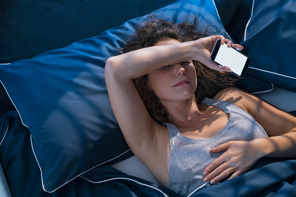 young woman holding phone while sleeping