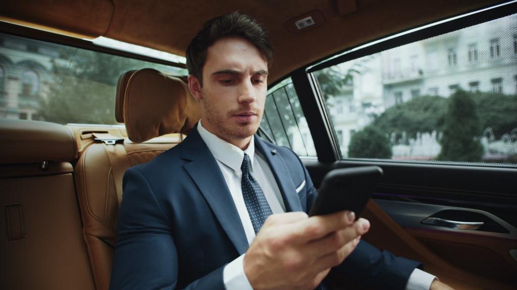 businessman frowning as he reads phone messages in an elegant car